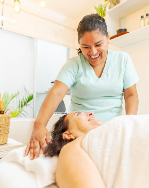 Vertical photo of a female adult latin masseur talking and smiling to a patient in spa clinic